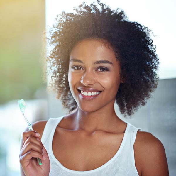 smiling young woman with toothbrush